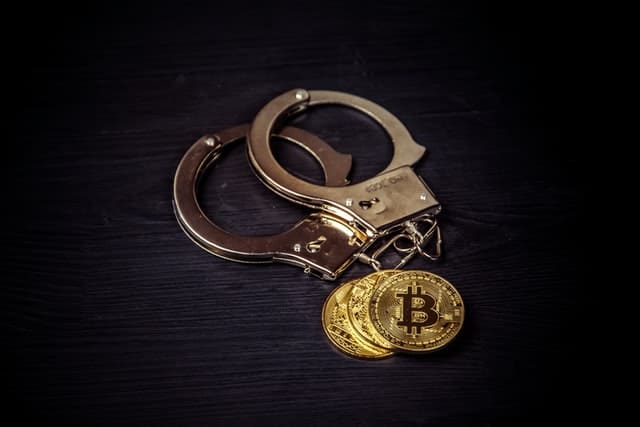 Handcuffs next to representation of Bitcoin